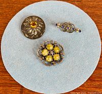 All three brooches on blue backing showing size and design