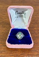 Ring in open Cousins box showing crest and box interior text