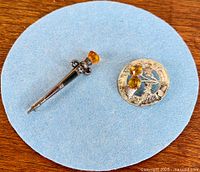 Both sterling silver brooches shown on blue felt