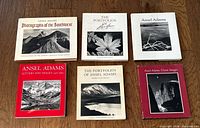 Six Ansel Adams books laid out on wood surface