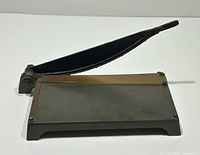 Top view of antique paper cutter showing base, blade arm, brass straightedge