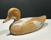 Profile view of unfinished wooden duck decoy showing overall form and filler patches