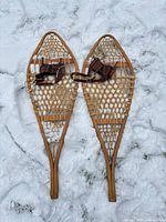 Full view of both wooden snowshoes on snow