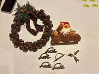 Group shot of wreath, plaque, six napkin rings, cross