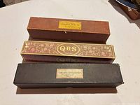 Three player-piano roll boxes stacked showing brand labels