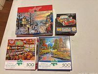 Group shot of four visible puzzle boxes: A Christmas Story 300-piece, shaped Corvette 100-piece, Rickie Pickett's Mercantile 500-piece, Dewie Hollow 500-piece