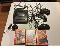 Entire lot laid out showing console, controllers, cables, and three boxed games