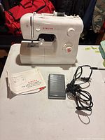 Singer 2250 sewing machine front with manual, foot pedal and cord