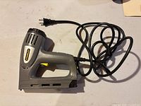 Left side view of Stanley corded stapler/brad nailer with coiled power cord visible