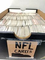 Front view of cardboard box filled with tightly packed trading cards, "NFL Cards" label visible