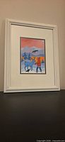 Framed Ted Harrison print on black surface