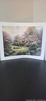Full view of unframed Thomas Kinkade print standing upright