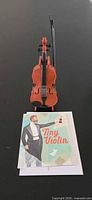 Miniature violin, bow, booklet on tabletop