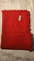 Folded red wool scarf showing fringe and tag