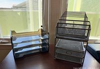 Plastic three-tier letter tray beside mesh organizer set