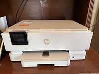 Front view of HP ENVY Inspire 7220e printer showing HP logo, touchscreen and output tray