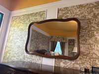 Front view of serpentine rectangular mirror mounted above dresser