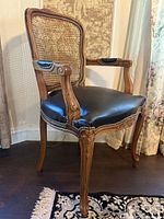 Front angled view showing cane back, leather seat, carving