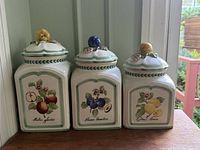 Front view of all three canisters showing fruit motifs and lid knobs