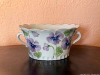 Front view of scalloped porcelain planter with pansy design and two handles