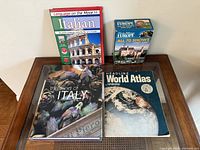 Overview of four items on table: Italian language book, Rick Steves DVD box, The Food of Italy book, Hammond World Atlas
