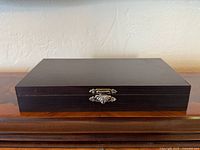 closed dark wood box front view showing decorative clasp