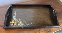 Top view of dark wooden tray showing floral design and handle cut-outs