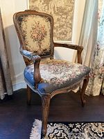 Full view of carved wood armchair with floral needlepoint upholstery