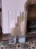 two clear glass cylinder vases, right vase contains glass beads