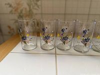Six clear tumblers side by side showing floral design