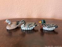 Three carved wooden duck figurines side by side