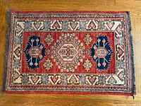 Full view of red, blue and ivory Heriz rug on hardwood floor