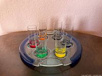 Seven-piece IVAT glass set displayed on table: round fused tray and six colored-base shot glasses