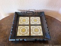 Top view of carved wood tray showing four ceramic tiles