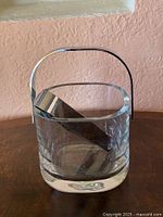 Glass ice bucket with handle and tongs placed inside