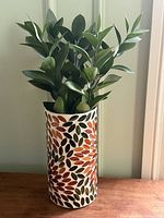 Full view of cylindrical mosaic vase with foliage for scale