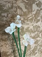 three glass flowers with green stems and white petals