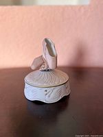 Front view of porcelain music box with ballet shoes topper