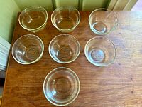 Seven clear glass bowls arranged on wooden surface