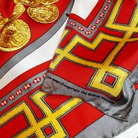 Close-up of gold coin and border detailing on red silk scarf