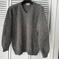 Front view of gray V-neck sweater on hanger