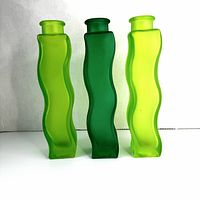 Front view of three squiggly green glass vases