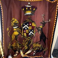 Full scarf showing burgundy field, heraldic coat of arms with lion and stag, crown, check border