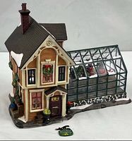 Front and side view of porcelain house with greenhouse and detached sign visible