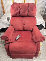 Front view of burgundy Pride power lift recliner with remote on seat