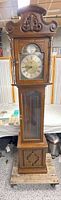 Full view of Ridgeway grandfather clock on pallet showing wood cabinet, glass door, lower cabinet