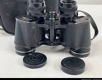 Front view of binoculars with lens caps and case