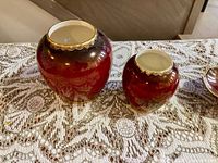 Two Carlton Ware Rouge Royale vases side by side on lace cloth