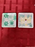 Two Ando cloisonne square dishes displayed side by side showing designs