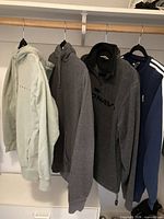 Four fleece tops hanging: mint green hoodie, dark grey hoodie, dark grey Old Navy quarter-zip, navy Adidas crew
